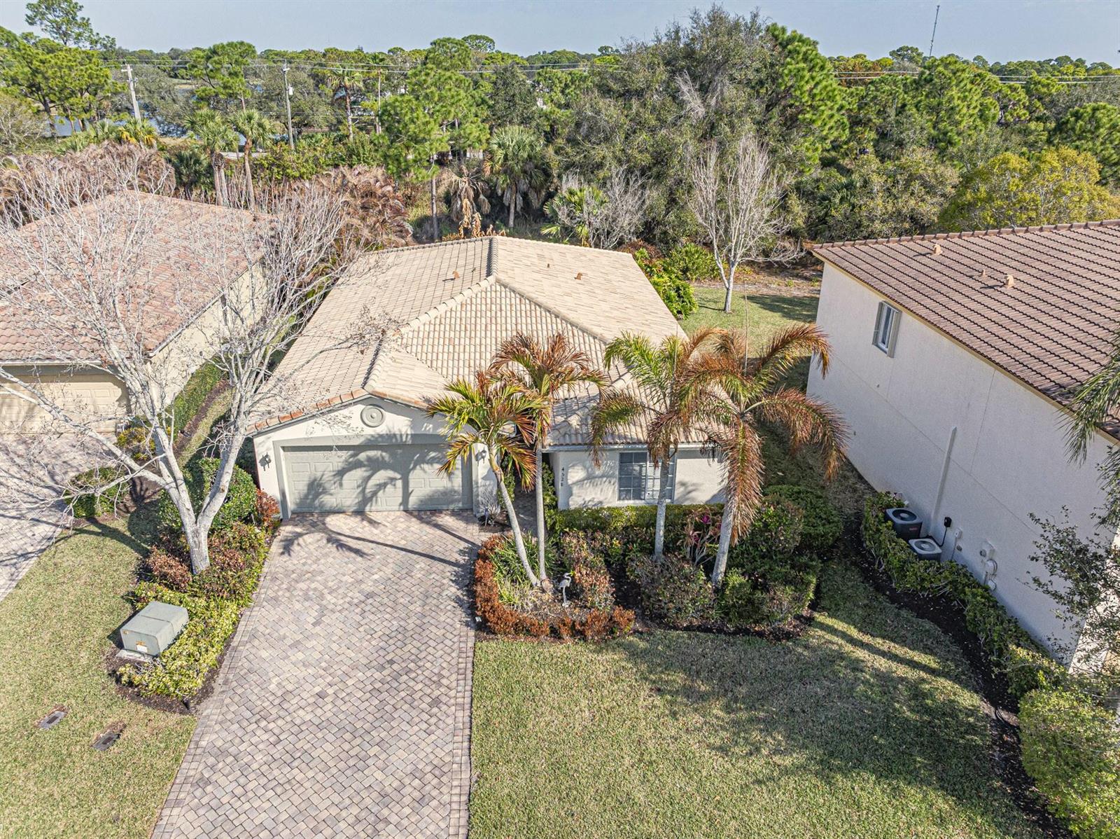 An aerial view shows a single-story house with a tiled roof, paver driveway, and palm trees — 4528 56th Lane, Vero Beach FL 32967, VERO BEACH, FL