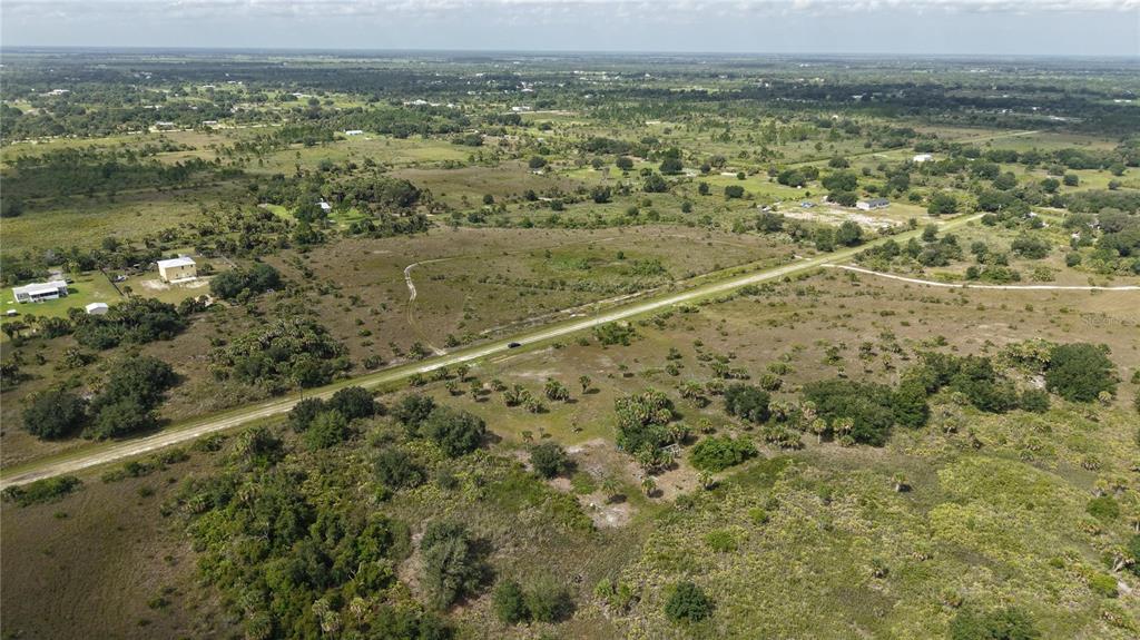 An aerial view shows a rural landscape with a paved road cutting through open land — 14773 NW 280TH STREET, OKEECHOBEE, FL