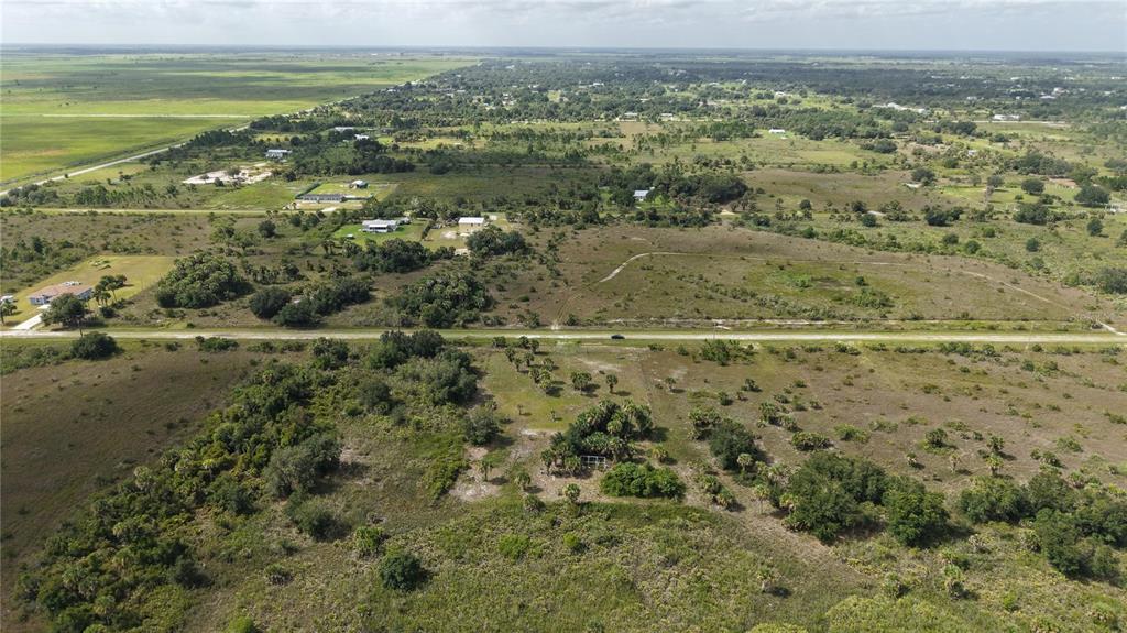 An aerial view shows a rural landscape with scattered houses, vegetation, and a paved road — 14773 NW 280TH STREET, OKEECHOBEE, FL