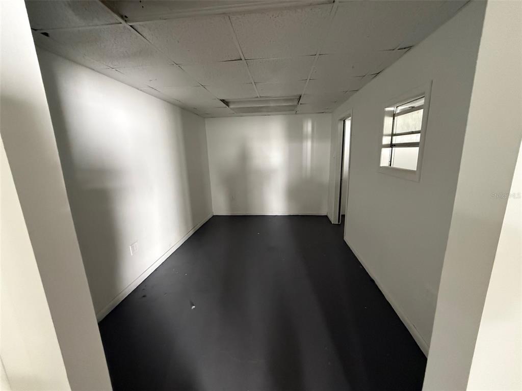 An empty room with white walls, a dark floor, and a drop ceiling — 14020 NW 19TH AVENUE, OPA LOCKA, FL