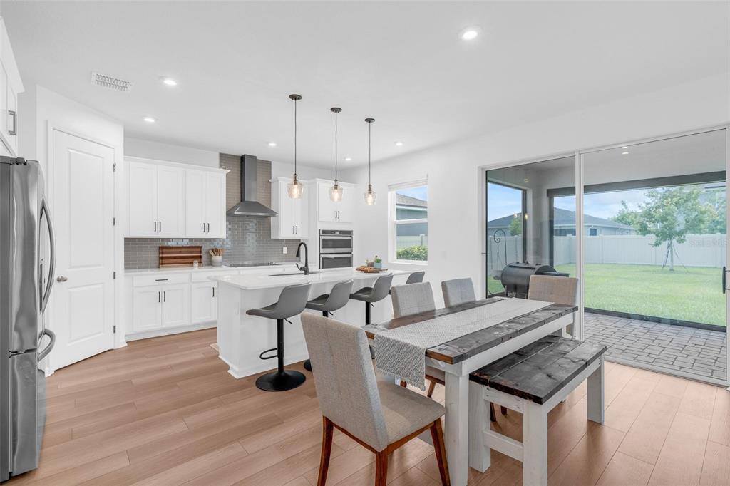 A modern kitchen with white cabinets, a center island, and an adjacent dining area — 2215 BLUE SALVIA STREET, CLERMONT, FL