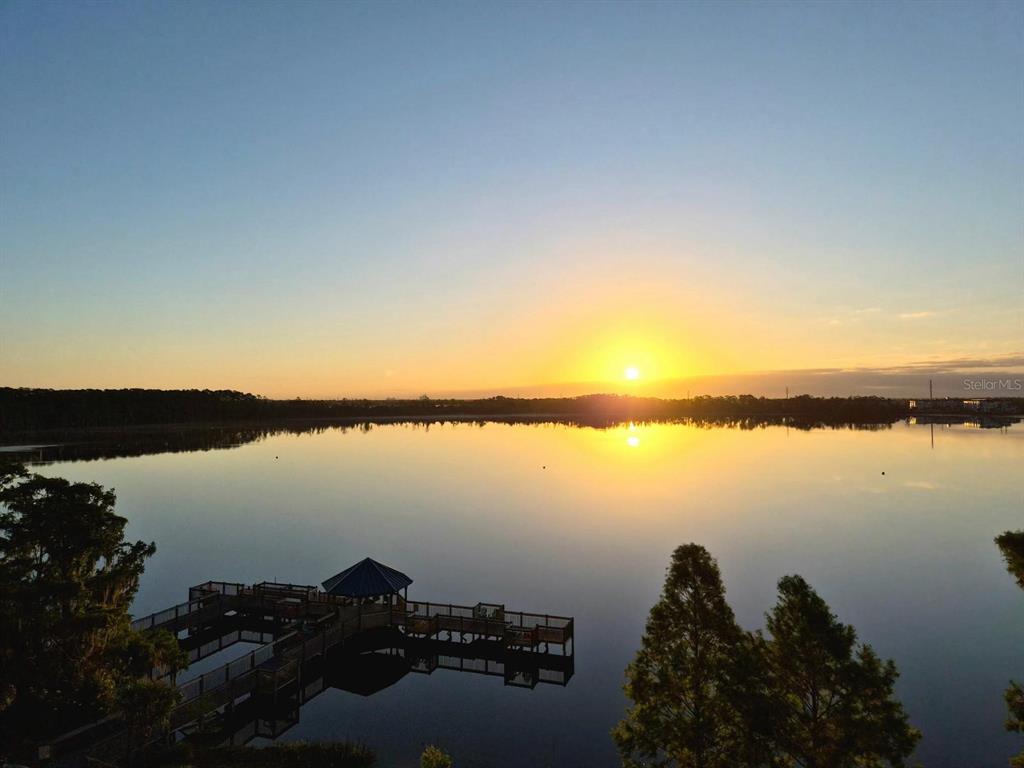 A wooden pier with a gazebo extends into a calm lake at sunset — 13427 BLUE HERON BEACH DRIVE UNIT 402, ORLANDO, FL