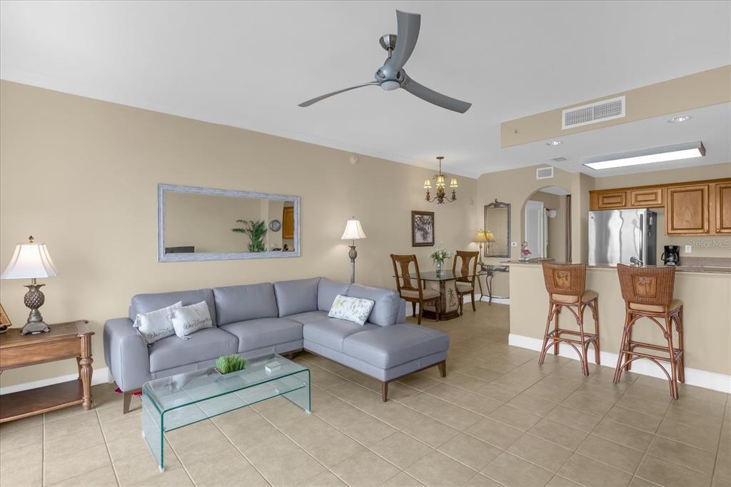 A living room and kitchen area with tile floors, a gray sectional, and bar stools — 13427 BLUE HERON BEACH DRIVE UNIT 402, ORLANDO, FL