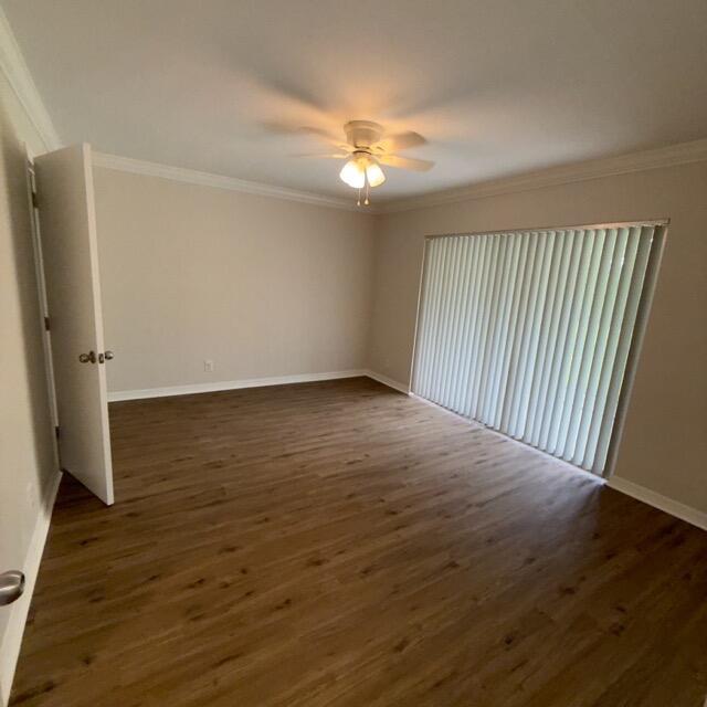 An empty bedroom features wood-look flooring, a ceiling fan, and vertical blinds over a sliding door — 1900 S Kanner Hwy Highway Apt 102, Stuart FL 34994, STUART, FL