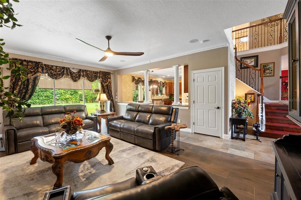 A foyer features a grand staircase with wood treads, tile flooring, and a double front door — 7445 MINNOW BROOK WAY, LAND O LAKES, FL