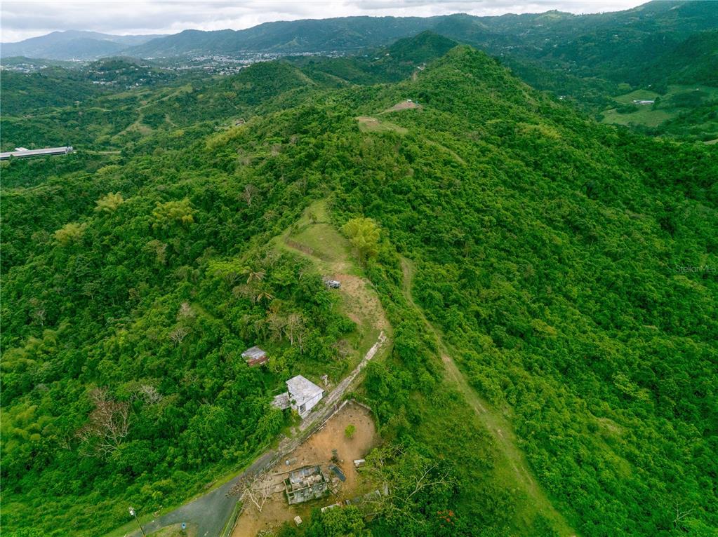 An aerial view shows a hillside property with a small house and surrounding green landscape — INTERIOR BO MATON ABAJO MATÓN ABAJO, CAYEY, PR