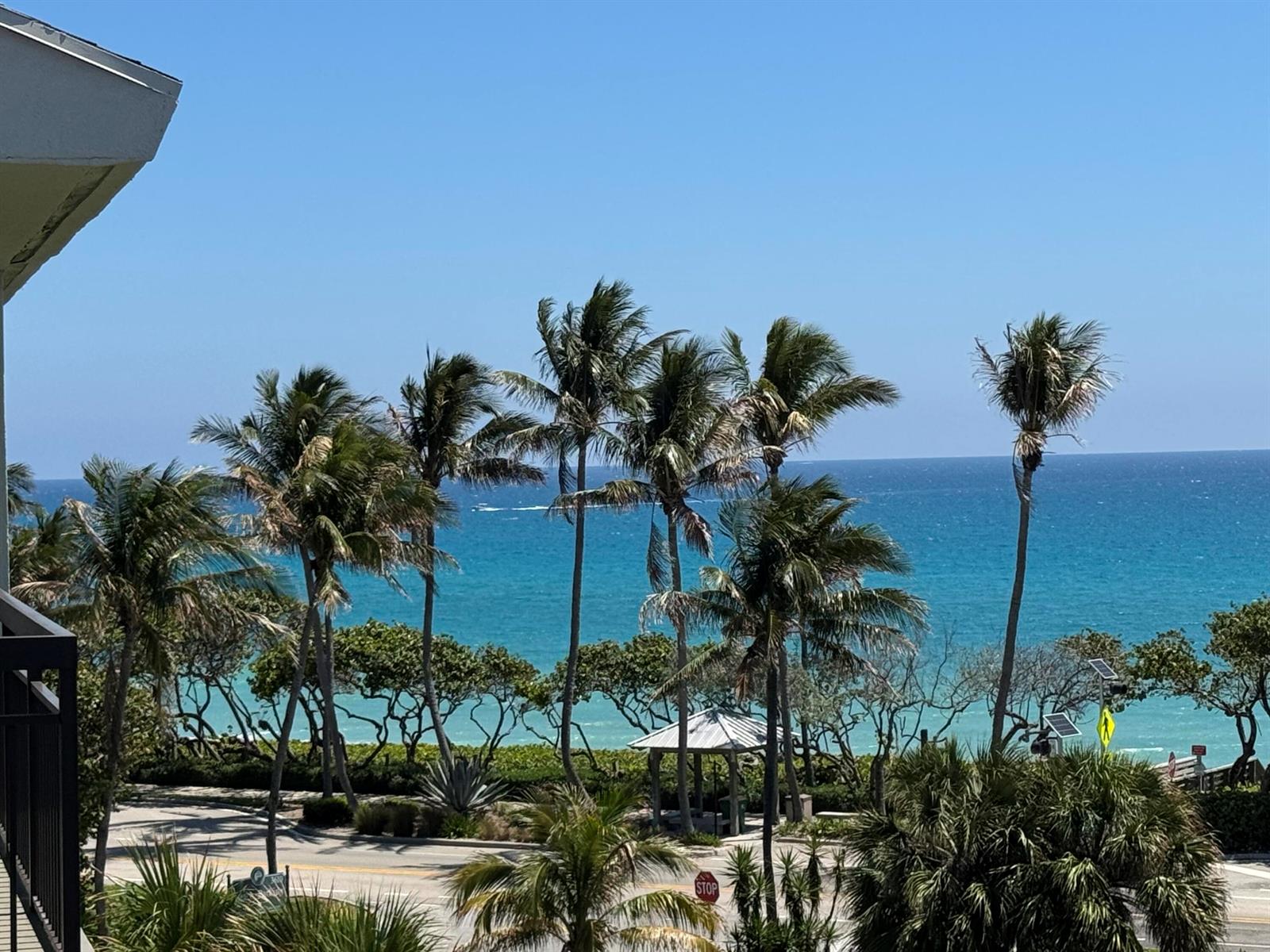A view of palm trees, a small gazebo, and the ocean from an elevated balcony — 101 S Seas Drive # 505, Jupiter FL 33477, JUPITER, FL