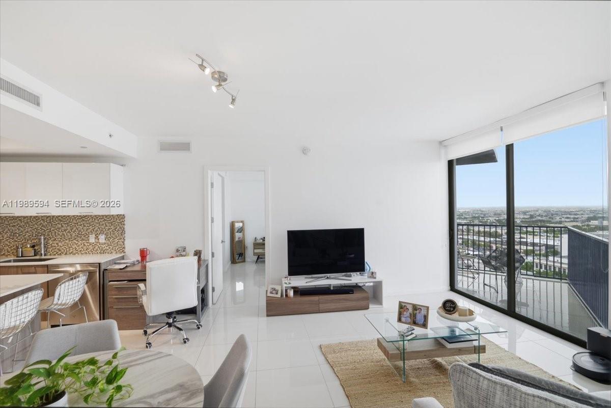 A modern living room with white tile floors, a glass coffee table, and a balcony — 5300 Paseo Blvd # 1803, Doral FL 33166, DORAL, FL