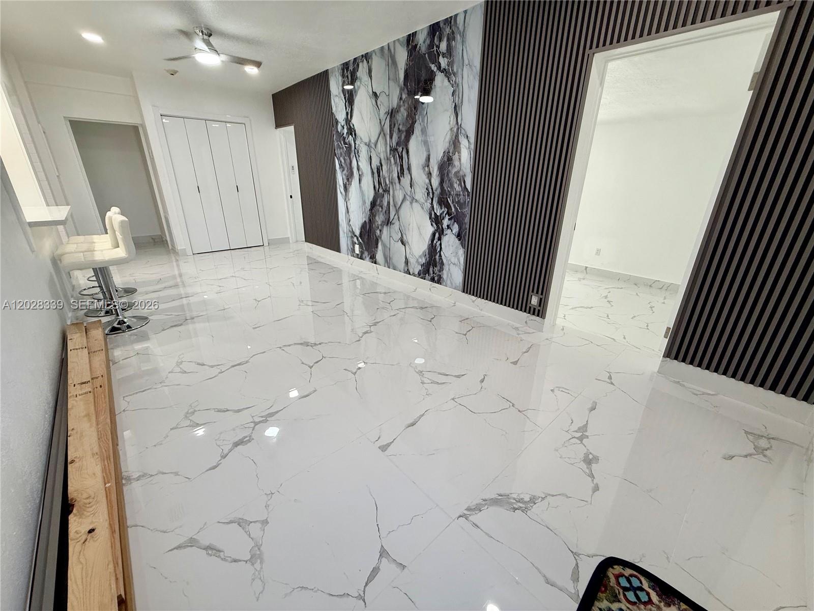 A room features white marble-patterned tile flooring, a dark wood-slatted wall, and marble paneling — 6520 W 8th Ln # 2, Hialeah FL 33012, HIALEAH, FL
