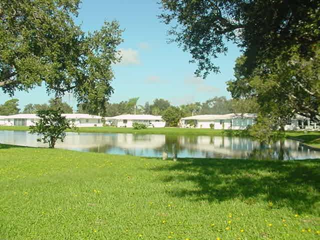 A grassy lawn overlooks a pond with several white residential buildings in the background — 519 CIRCLEWOOD DRIVE UNIT 519, VENICE, FL