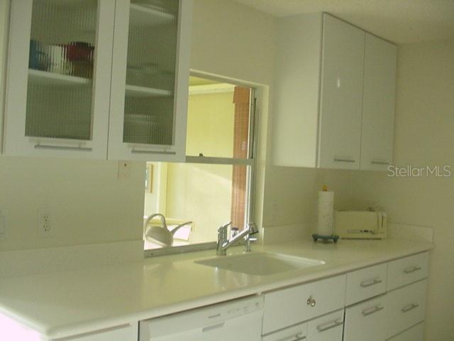 A kitchen features white cabinets, a white countertop, a sink, and a window — 519 CIRCLEWOOD DRIVE UNIT 519, VENICE, FL