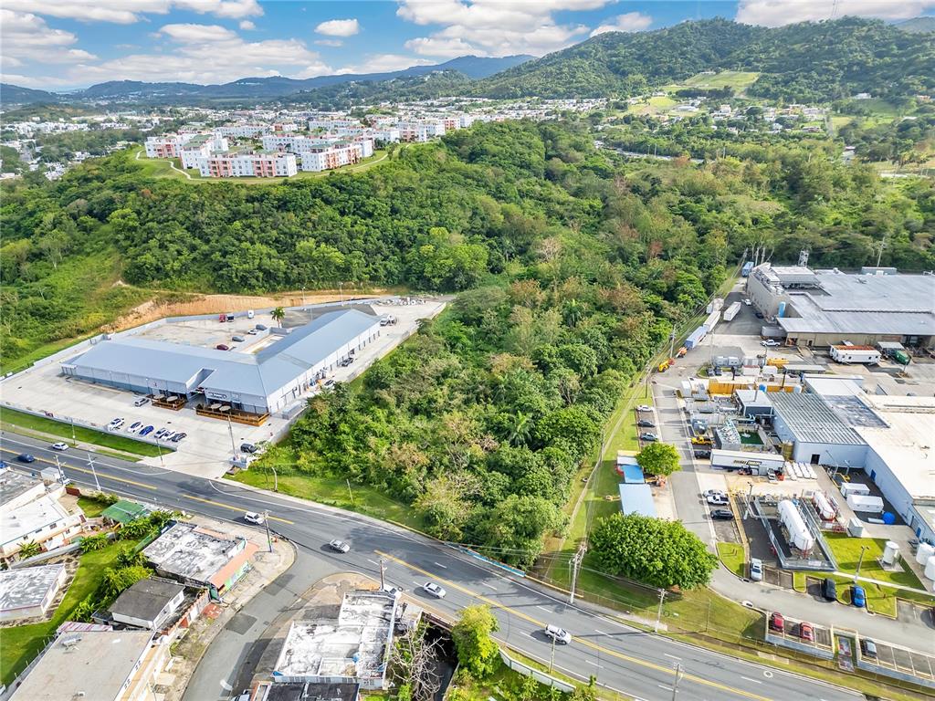An aerial view shows a commercial building, a wooded lot, and an industrial facility — PR-194 KM 0.9, FAJARDO, PR