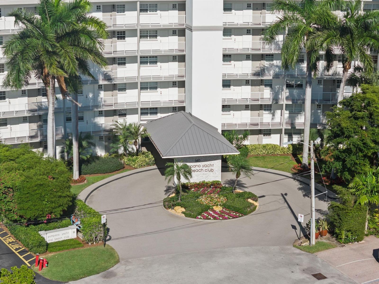 An aerial view shows the entrance of a multi-story apartment building with a circular driveway — 140 NE 28th Avenue # 406, Pompano Beach FL 33062, POMPANO BEACH, FL