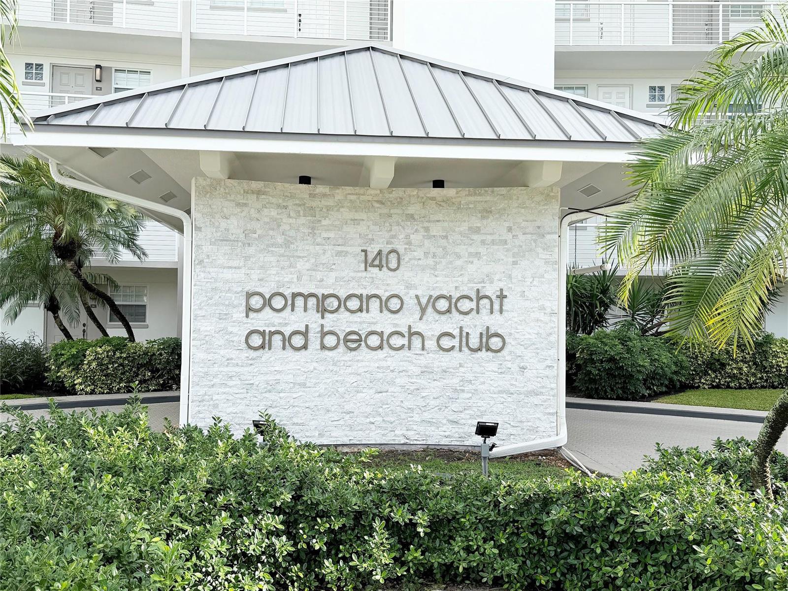 A stone monument sign for the Pompano Yacht and Beach Club stands under a metal roof — 140 NE 28th Avenue # 406, Pompano Beach FL 33062, POMPANO BEACH, FL