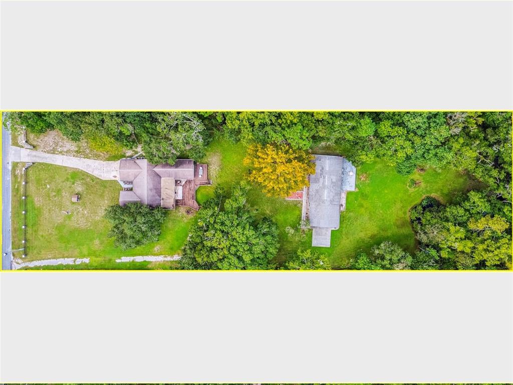 A single-story house with gray siding sits on a large, grassy lot surrounded by trees — 9741 STAR TRAIL, NEW PORT RICHEY, FL