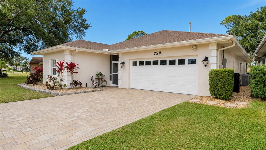 A single-story house with a paved driveway, a two-car garage, and landscaped front yard — 728 CANBERRA ROAD, WINTER HAVEN, FL