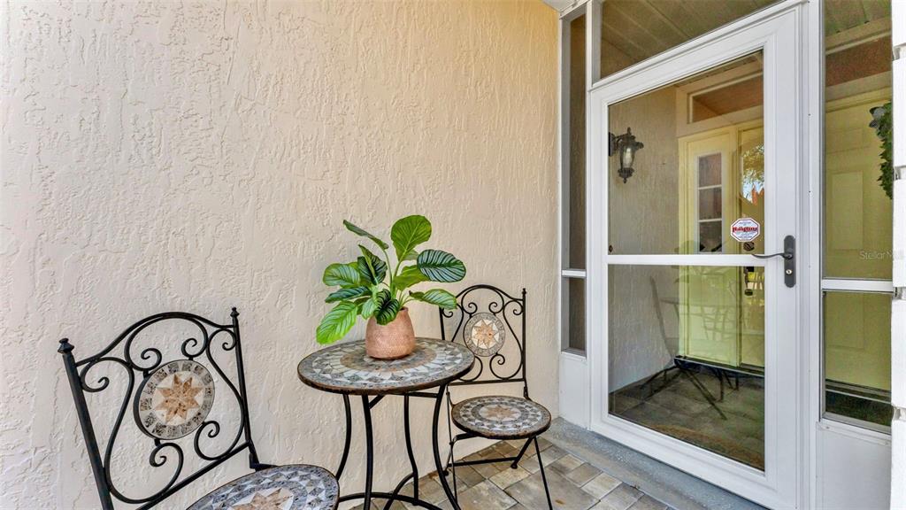 A small patio features two metal chairs and a round mosaic table with a plant — 728 CANBERRA ROAD, WINTER HAVEN, FL