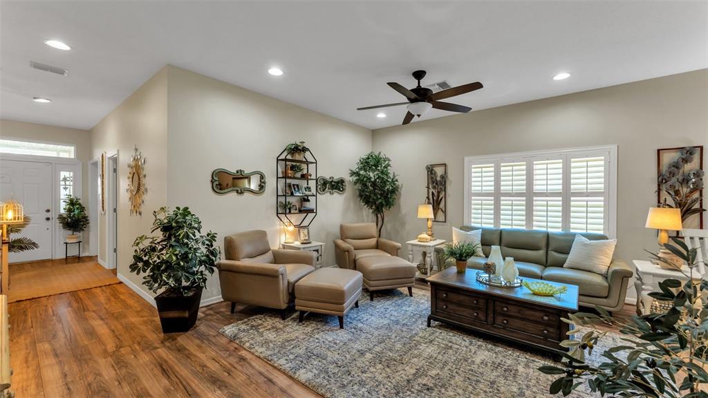 A living room features light-colored walls, wood-look flooring, a ceiling fan, and neutral furniture — 728 CANBERRA ROAD, WINTER HAVEN, FL