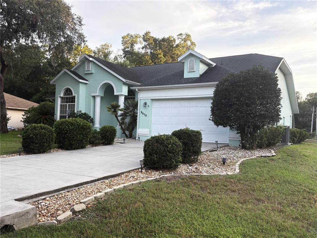 A light green single-story house with a white garage and a concrete driveway — 9670 SW 190TH TERRACE ROAD, DUNNELLON, FL