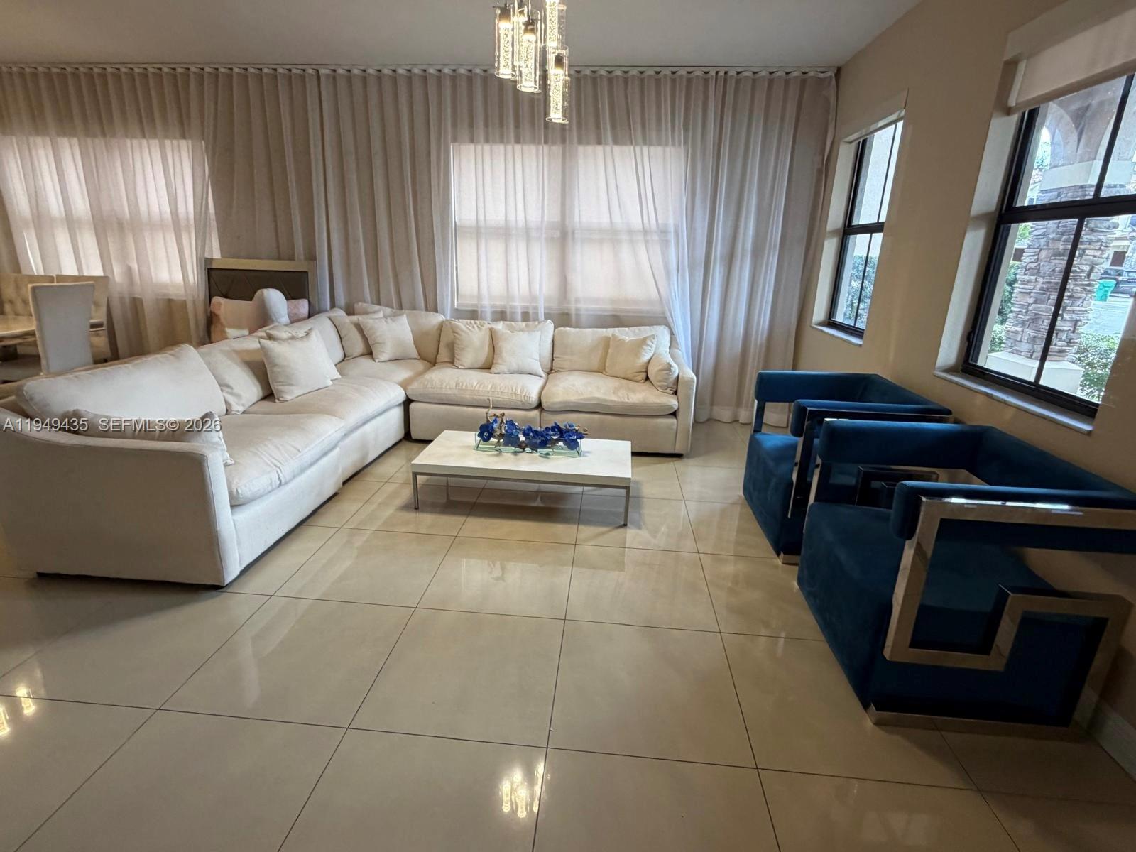 A living room features a large white sectional sofa, two blue armchairs, and tile flooring — 9855 NW 89th Ter, Doral FL 33178, DORAL, FL