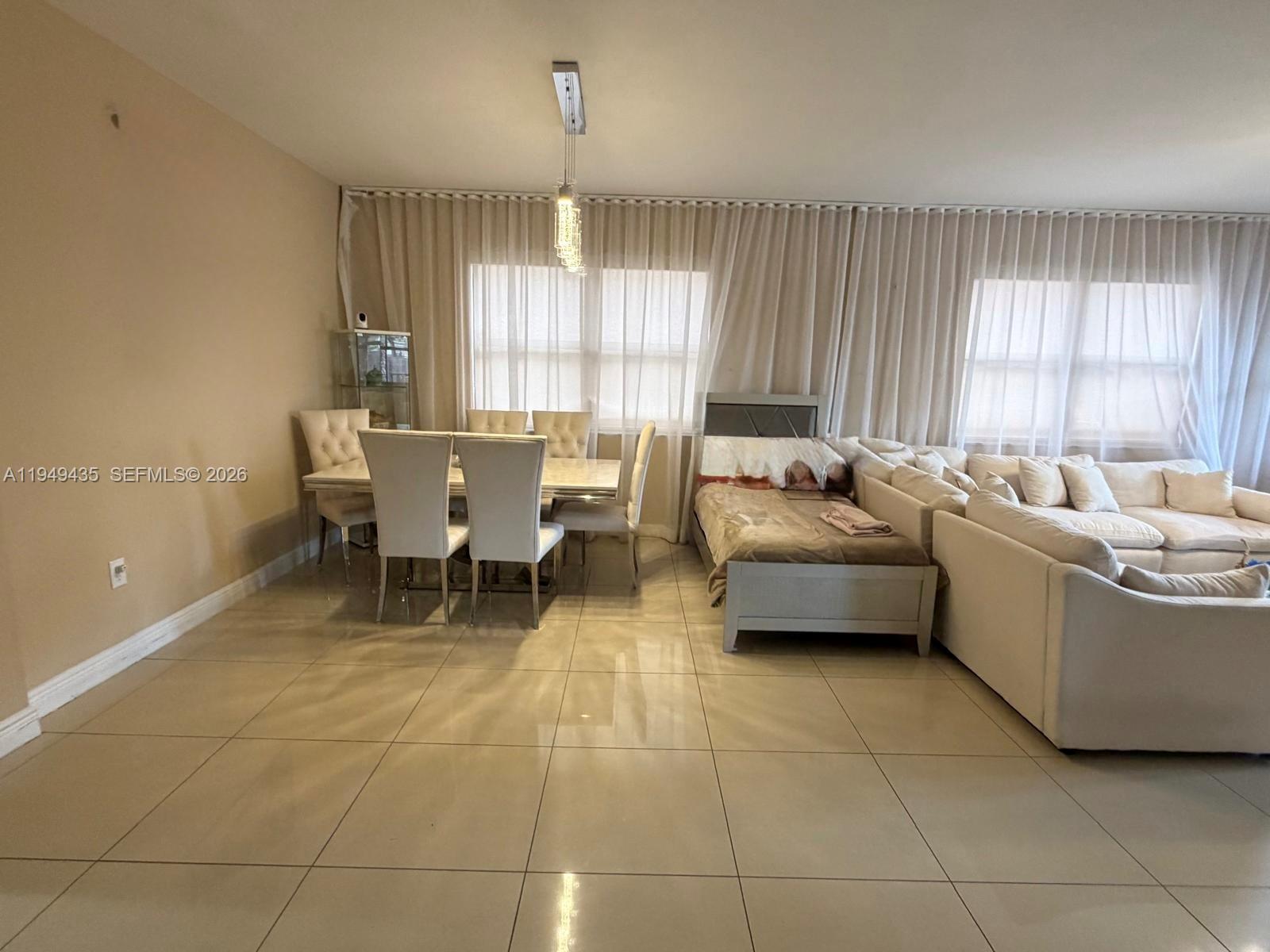 A room with light-colored tile floors features a dining set and a sofa bed — 9855 NW 89th Ter, Doral FL 33178, DORAL, FL
