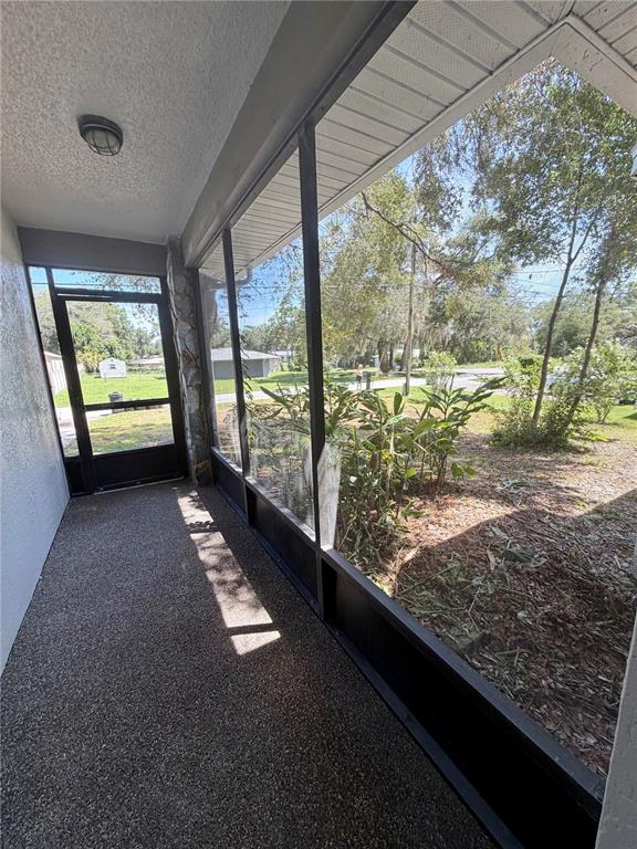 A screened-in porch with a textured concrete floor and views of a grassy yard — 115 DAFFODILL STREET, INVERNESS, FL