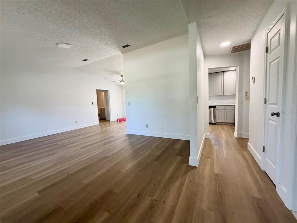 An interior view shows a living area with light wood-look flooring and a kitchen beyond — 115 DAFFODILL STREET, INVERNESS, FL