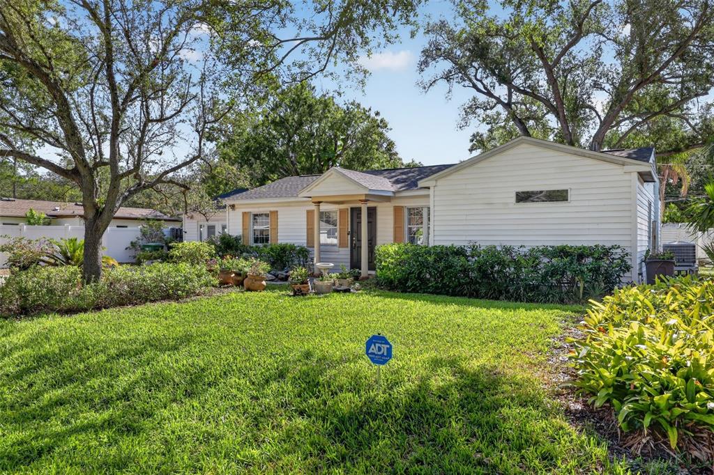 A single-story white house with a front porch, lawn, and large trees in the yard — 4204 S RENELLIE DRIVE, TAMPA, FL