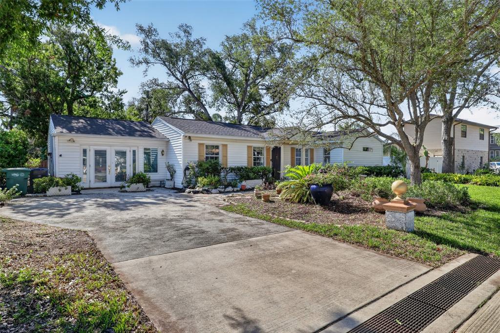 A single-story white house with a concrete driveway and mature trees in the front yard — 4204 S RENELLIE DRIVE, TAMPA, FL