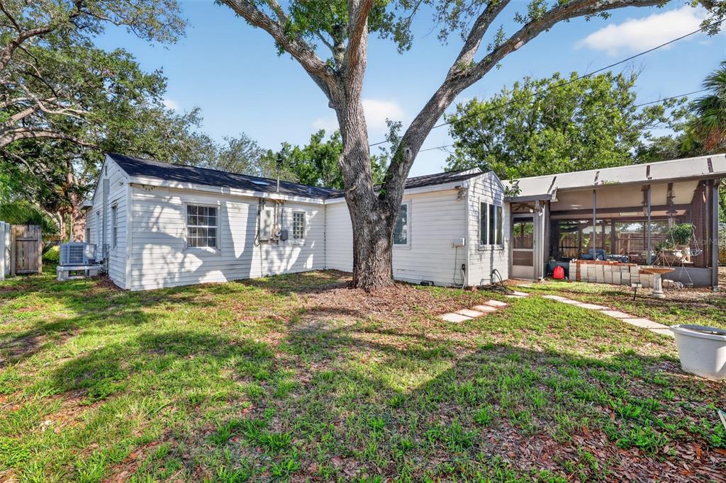 The exterior of a white house features a large tree and a screened-in porch — 4204 S RENELLIE DRIVE, TAMPA, FL