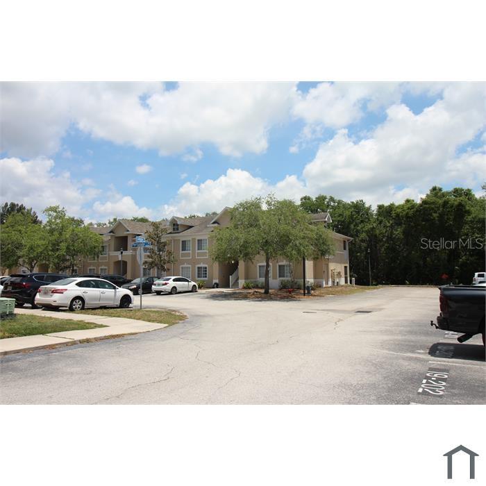 A multi-story apartment building with a parking lot in the foreground — 6022 PORTSDALE PLACE UNIT 202, RIVERVIEW, FL