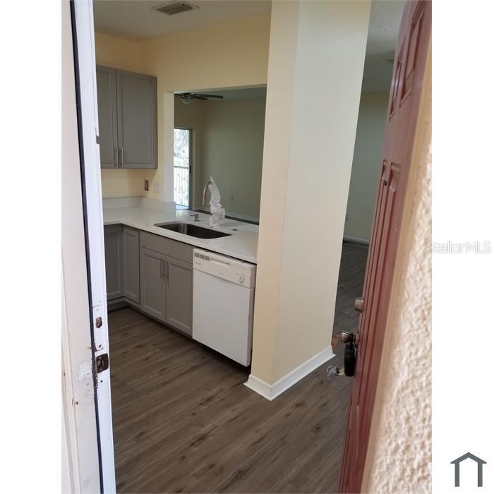 A kitchen with gray cabinets, white countertops, and wood-look flooring viewed from a doorway — 6022 PORTSDALE PLACE UNIT 202, RIVERVIEW, FL