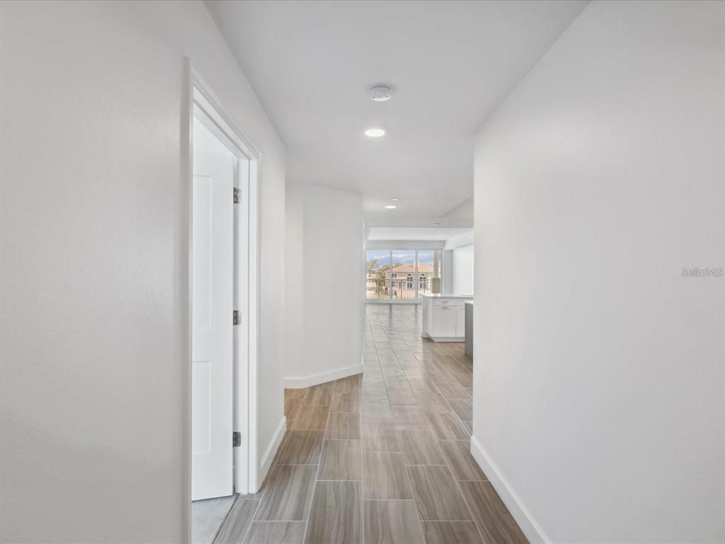 A hallway with wood-look tile flooring leads to an open-concept kitchen and living area — 125 ISLAND WAY UNIT 304, CLEARWATER BEACH, FL