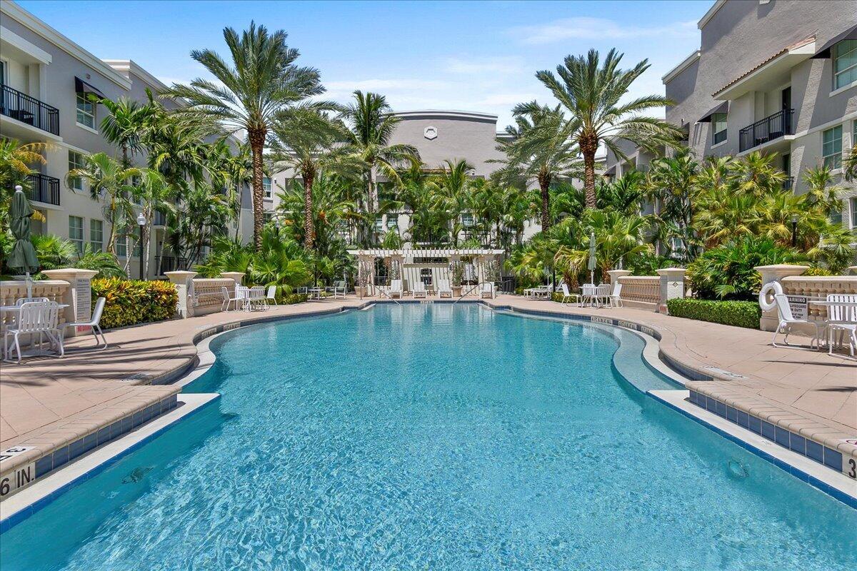 A swimming pool is surrounded by palm trees and multi-story apartment buildings — 600 S Dixie Highway # 825, West Palm Beach FL 33401, WEST PALM BEACH, FL