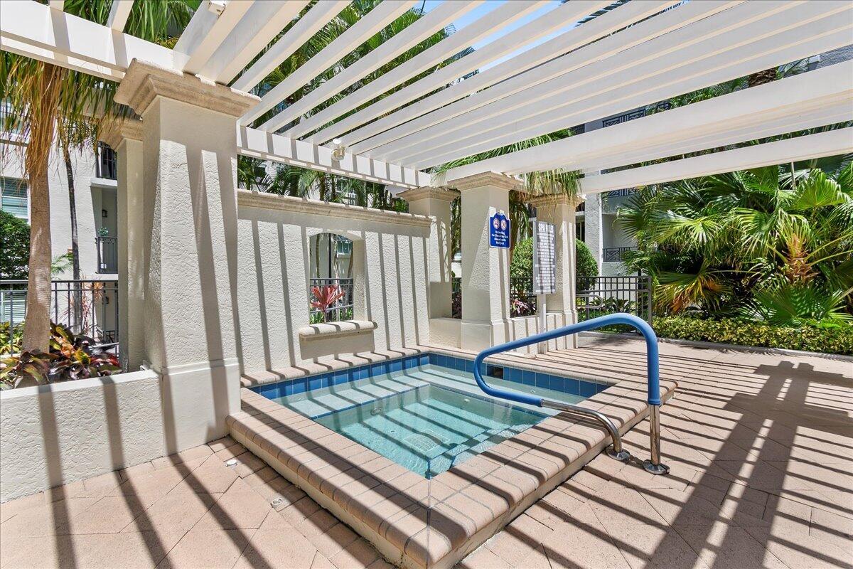 An outdoor hot tub sits beneath a white pergola on a paved pool deck — 600 S Dixie Highway # 825, West Palm Beach FL 33401, WEST PALM BEACH, FL