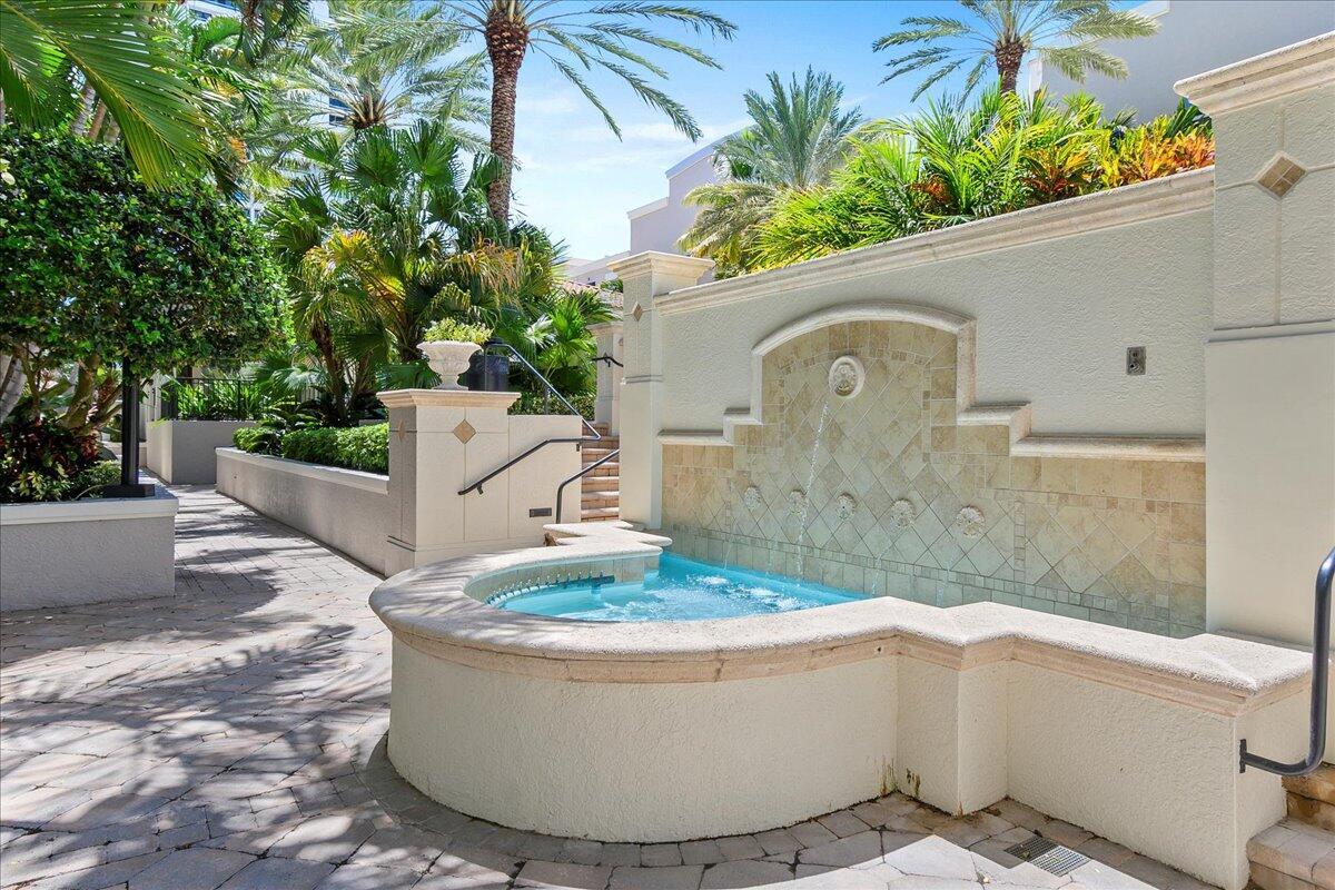 A stone fountain with a small pool sits on a paved patio surrounded by palm trees — 600 S Dixie Highway # 825, West Palm Beach FL 33401, WEST PALM BEACH, FL