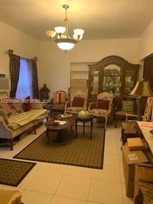 A living room with a chandelier, patterned rug, sofa, armchairs, and a wooden china cabinet — 809 NE 140th St, North Miami FL 33161, NORTH MIAMI, FL