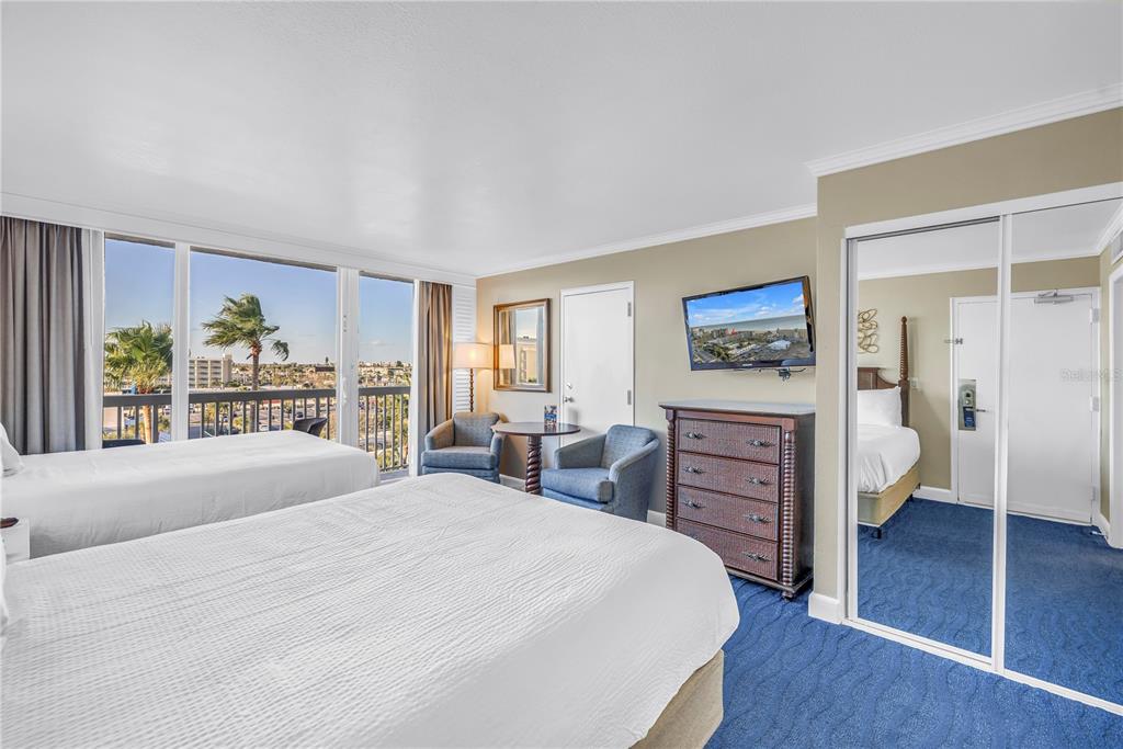 A hotel room features two beds, blue carpeting, a dresser with a television, and a balcony — 5500 GULF BOULEVARD UNIT 6248, ST PETE BEACH, FL
