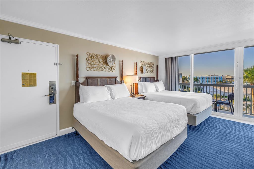 A hotel room features two beds, blue patterned carpeting, and a balcony with exterior views — 5500 GULF BOULEVARD UNIT 6248, ST PETE BEACH, FL