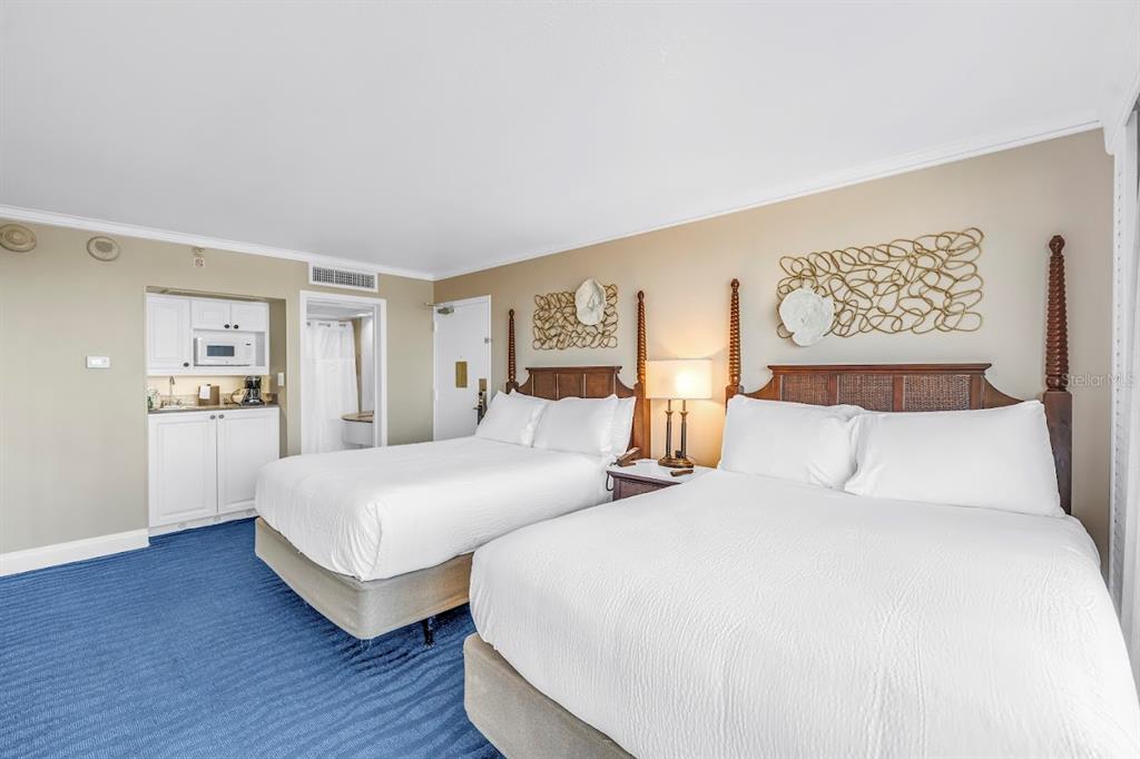 A hotel room features two beds, a small kitchenette, and blue carpet — 5500 GULF BOULEVARD UNIT 6248, ST PETE BEACH, FL