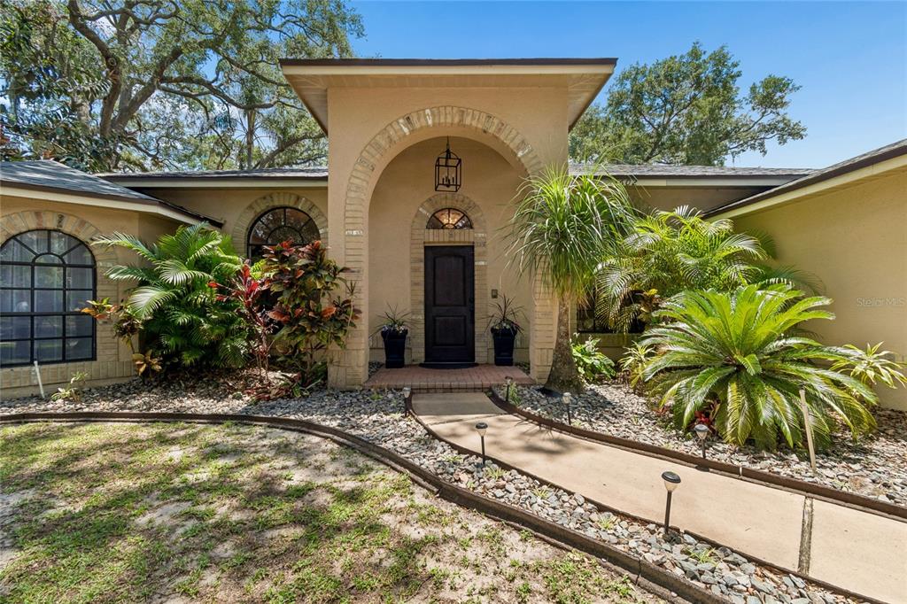 The front exterior of a house features a brick-arched entryway and a concrete walkway — 3602 ARLINGTON OAKS COURT, TAMPA, FL