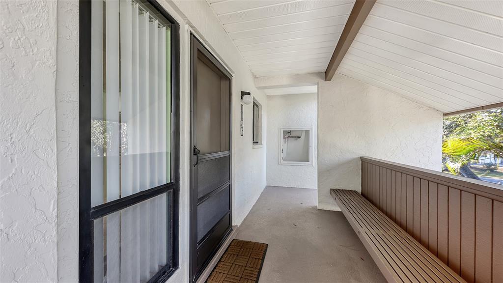 A covered outdoor entryway features a brown bench, a screen door, and a large window — 1196 BIRD BAY WAY UNIT 310, VENICE, FL