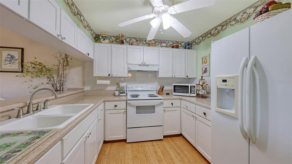A kitchen features white cabinetry, a white stove, a white refrigerator, and light-colored countertops — 1196 BIRD BAY WAY UNIT 310, VENICE, FL