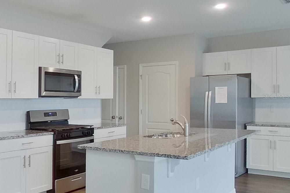 A kitchen features white cabinets, granite countertops, a central island, and stainless steel appliances — 31978 KATELIN CIRCLE, LEESBURG, FL
