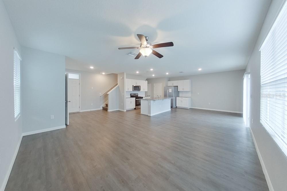 An open-concept living area features light gray walls, wood-look flooring, and a kitchen with white cabinets — 31978 KATELIN CIRCLE, LEESBURG, FL