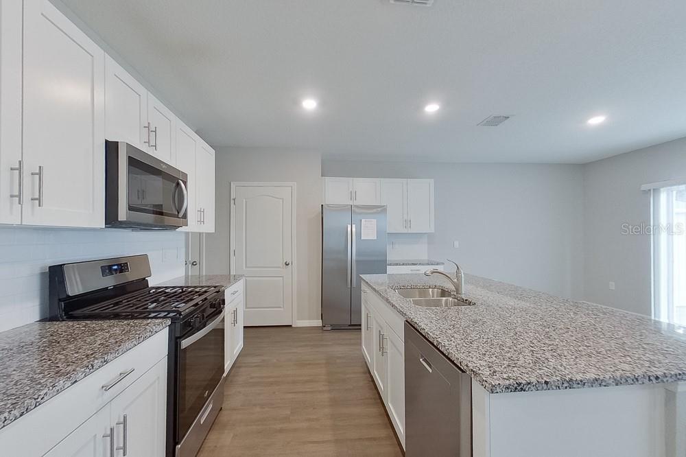 A kitchen features white cabinets, granite countertops, stainless steel appliances, and a large center island — 31978 KATELIN CIRCLE, LEESBURG, FL
