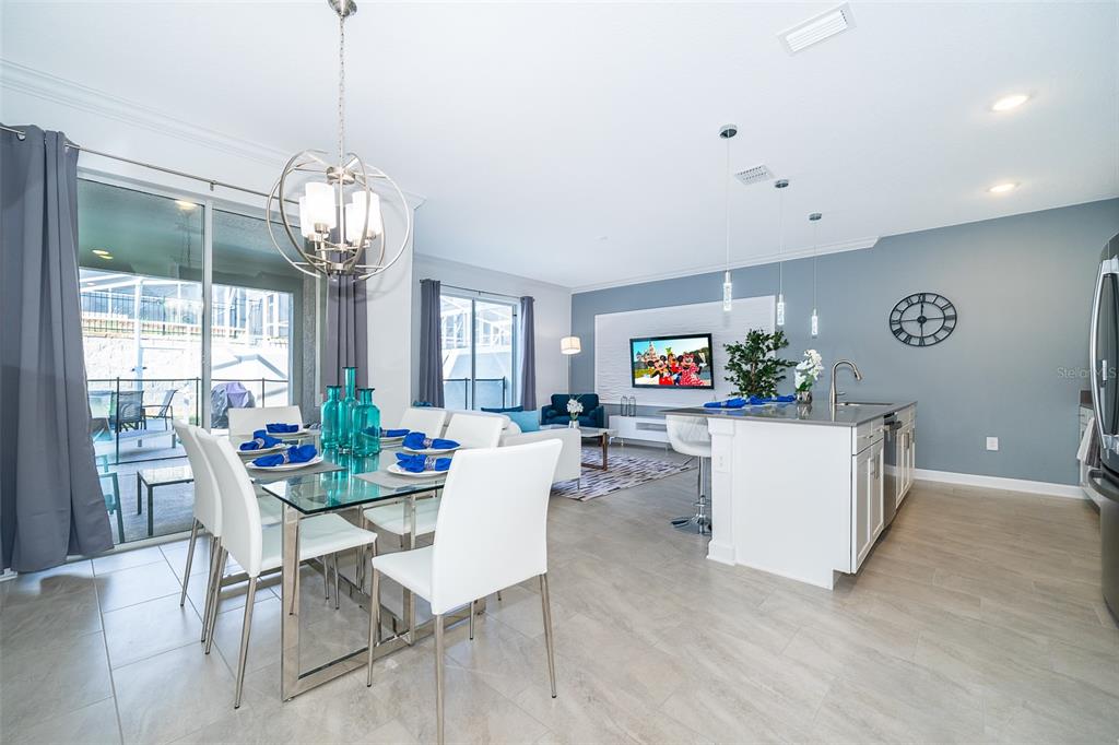 An open-concept dining and kitchen area features a glass table, white chairs, and gray walls — 1164 KINGSBARN STREET, DAVENPORT, FL