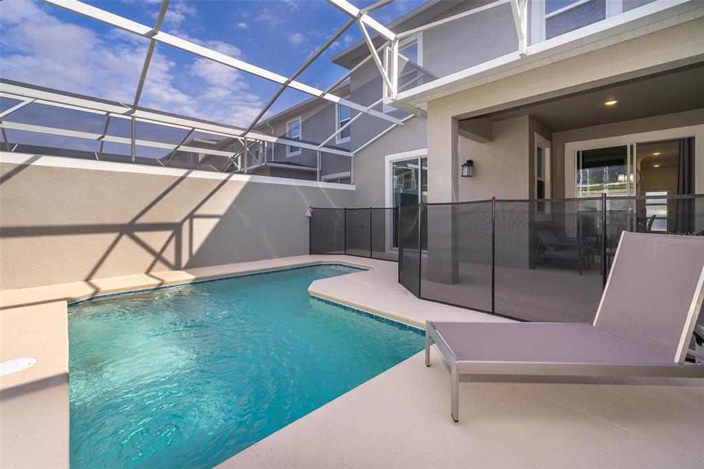 A screened-in patio features a swimming pool, a safety fence, and a lounge chair — 1164 KINGSBARN STREET, DAVENPORT, FL
