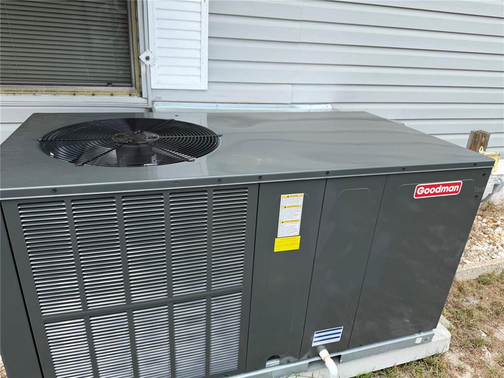A Goodman brand HVAC unit sits on a concrete pad outside a house — 4038 ROLLING OAKS DRIVE, WINTER HAVEN, FL