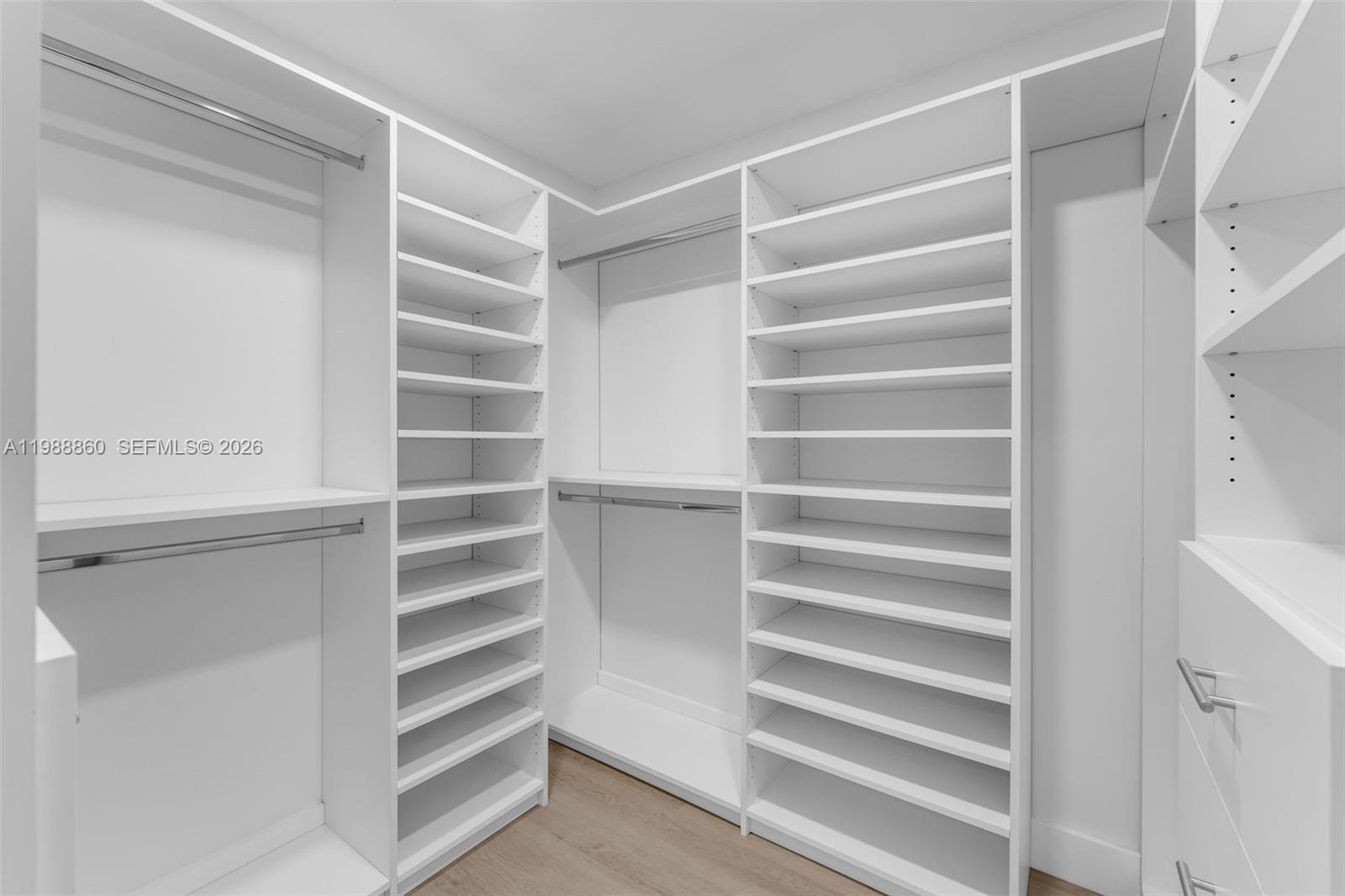 A walk-in closet features white shelving units, hanging rods, and light wood-look flooring — 10021 SW 145th Pl, Miami FL 33186, MIAMI, FL